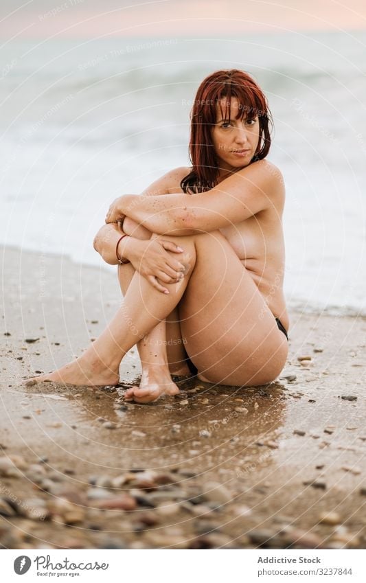 Nackte Frau sitzt in der Nähe von Meereswellen nackt MEER erotisch sexy sinnlich frei verführerisch oben ohne Eleganz Brust Körper Haut entkleidet unbedeckt