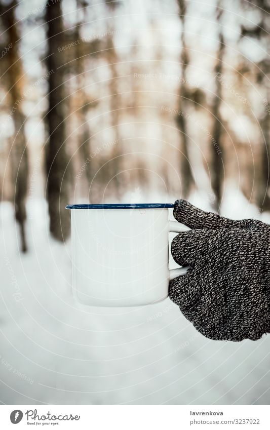 Männerhand im Strickhandschuh mit weißem Emailbecher Jahreszeiten kalt Erkältung Handschuhe gestrickt Natur frisch Morgen Holz Wald Außenaufnahme vertikal