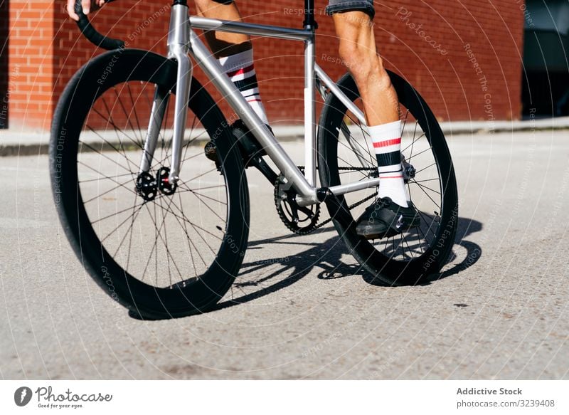 Sportlicher Mann fährt Fahrrad neben Ziegelmauer Backsteinwand Mitfahrgelegenheit modern Reiten sportlich aktiv Sommer männlich gutaussehend Radfahrer Erholung