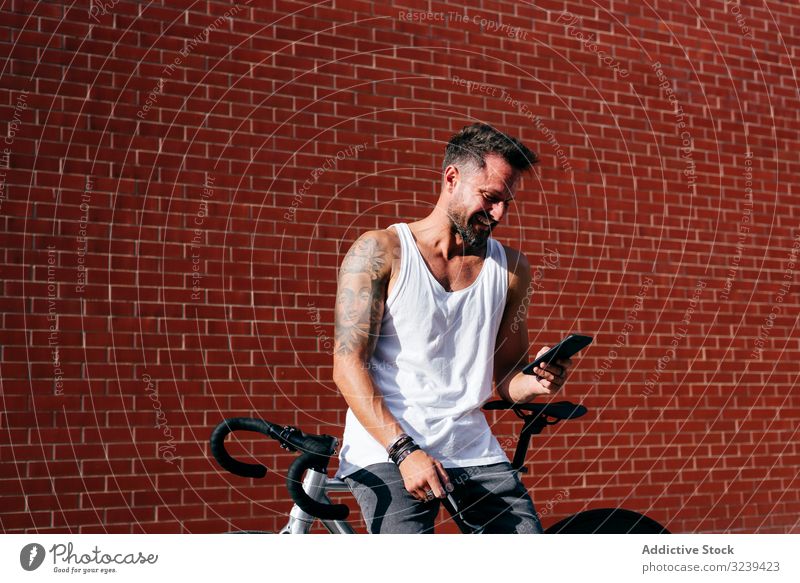 Sportlicher Mann mit Fahrrad beim Telefonieren stehen Handy benutzend modern sportlich aktiv Sommer männlich Radfahrer Smartphone Nachricht Texten Überprüfung