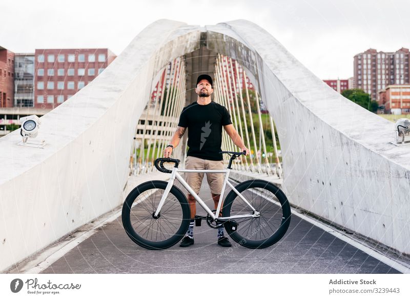 Fröhlicher Mann mit Fahrrad auf Steg stehend Großstadt Mitfahrgelegenheit Brücke modern aktiv sportlich Sommer männlich Erwachsener Glück heiter Lächeln