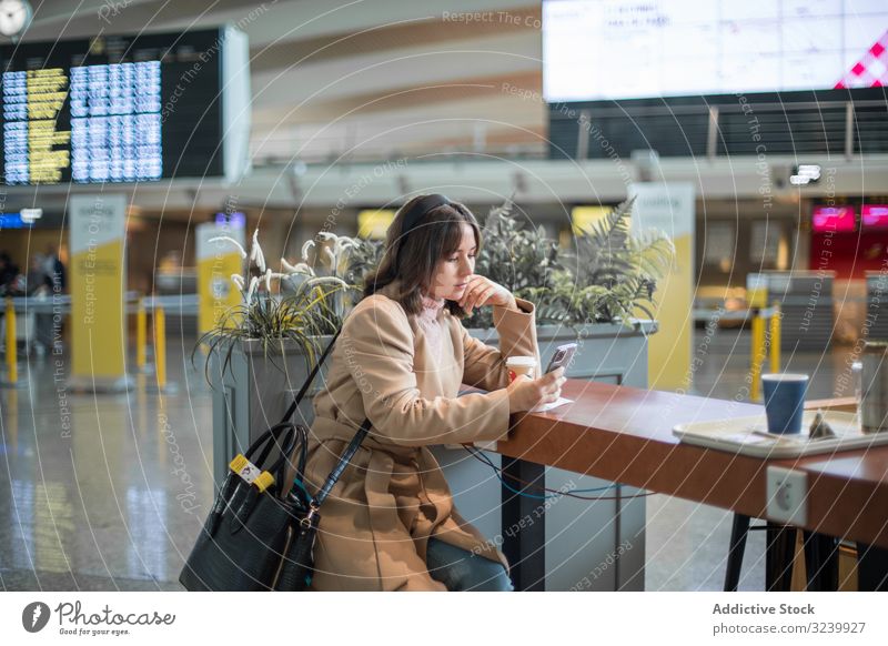 Dame sitzt und benutzt Smartphone am Flughafen Frau Warteraum Flugzeug Abheben benutzend Reisender Kaffee Telefon Browsen Terminal Mobile zuschauend Surfen