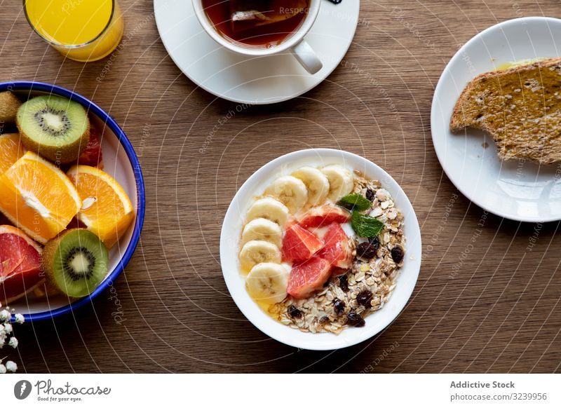 Saft und Teller mit Müsli und Früchten auf dem Tisch Frucht Büffet Mahlzeit aufgeschnitten Zitrusfrüchte Frühstück Erdbeeren Banane Tee Gesundheit orange