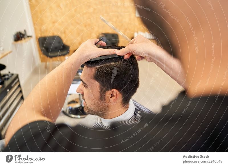 Friseur schneidet einem Kunden die Haare im Sitzen auf der Friseurcouch geschnitten Barbershop Kamm Frisur Möbel Arbeit Dienst professionell Hände Waffen nass
