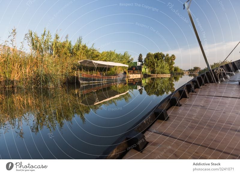 Seite eines modernen Bootes, das an einer ländlichen Küste entlangfährt Segel Ufer Gefäße Mitfahrgelegenheit ruhig sonnig Lagune Valencia Reflexion & Spiegelung