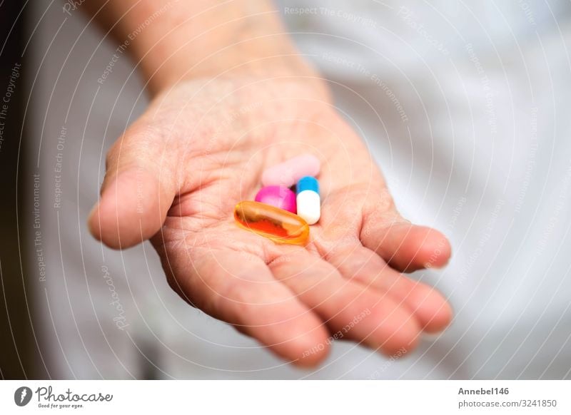 Viele mehrfarbige Pillen in den Händen eines Seniors. Schmerzhaftes Alter. Flasche Gesundheitswesen Behandlung Krankheit Medikament Krankenhaus Mensch Frau