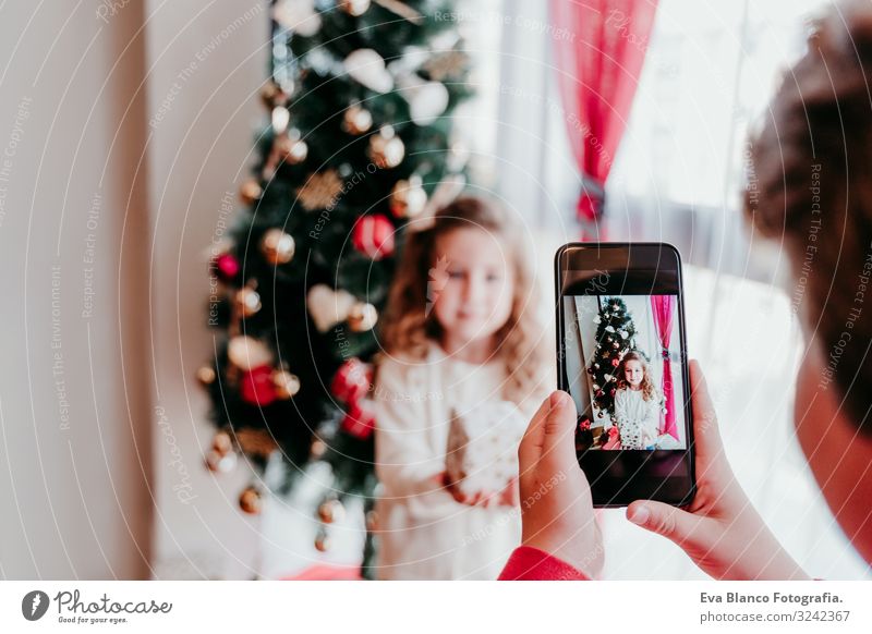 Bruder macht ein Foto von seiner Schwester mit dem Handy. Lifestyle Freude Spielen Winter Haus Weihnachten & Advent PDA Bildschirm Technik & Technologie Mensch