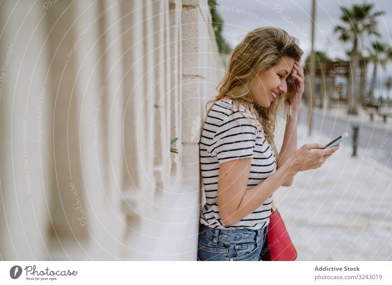 Frau telefoniert auf der Straße in der Stadt Telefon benutzend Großstadt lesen Glück Lächeln jung heiter zufrieden freudig Lachen positiv Smartphone Mobile