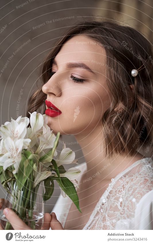 Sinnliche Frau mit roten Lippen, die weiße Blumen hält und träumt weißes Kleid Brautkleid sinnlich sanft rote Lippen Make-up träumen Charme Angebot Schönheit