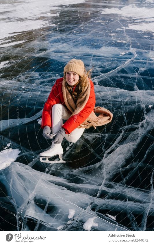 Frau sitzt auf gefrorenem Fluss und bindet sich die Schnürsenkel Schnee Stiefel das Binden der Schnürsenkel Schlittschuhe anmachend Winter Wandel & Veränderung