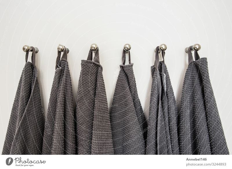 Graue Handtücher in einer Reihe hängend, auf Kleiderbügel vorbereitet. weiße Wand Spa Ferien & Urlaub & Reisen Haus Bad Stoff Metall Stahl Sauberkeit weich grau