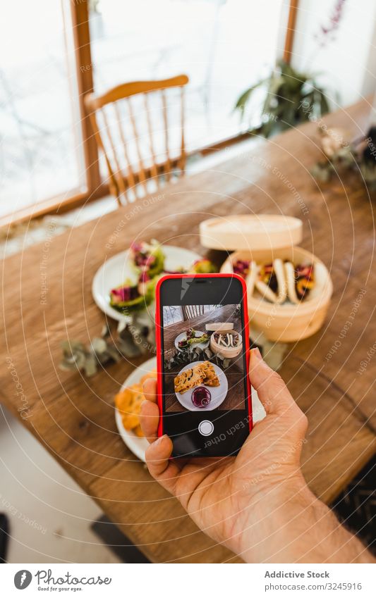 Fotograf beim Fotografieren von Lebensmitteln mit Smartphone fotografierend Food-Fotografie Bild Hand Mobile Funktelefon Telefon Tisch Mahlzeit Teller Speise