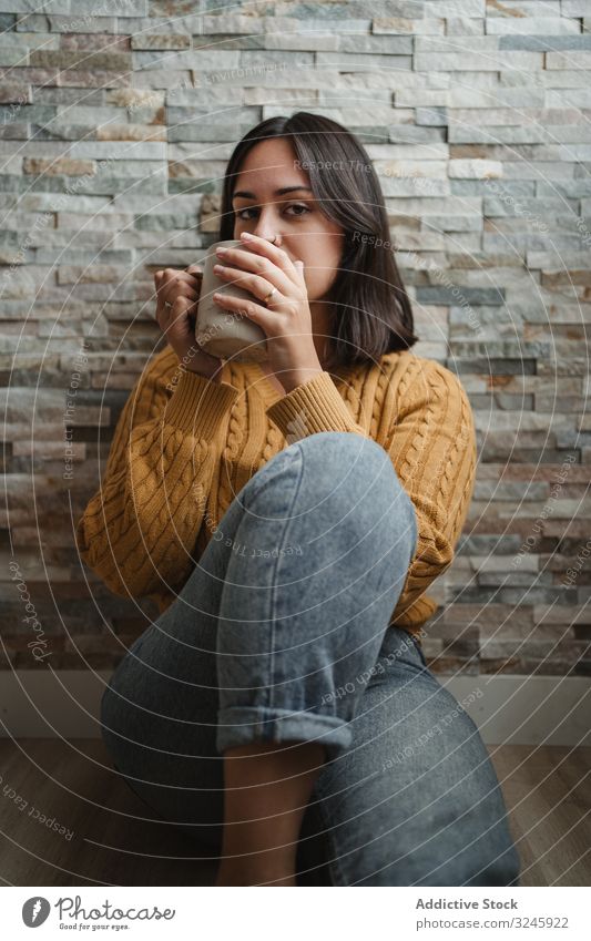Frau trinkt zu Hause heißen Tee trinken Becher Pullover Kaffee heimwärts sitzen Stock Jeanshose Tasse Getränk jung Halt sich[Akk] entspannen genießen Erholung