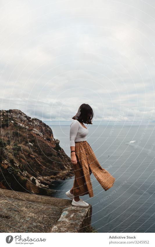 Einsame Frau steht auf Klippe vor bewölktem Himmel Küste Höhe Freiheit Wasser Gleichgewicht Aussichtspunkt Hochland Gefahr MEER frisch Einsamkeit