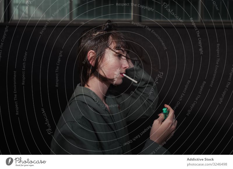 Weiblicher Teenager in Freizeitkleidung raucht Zigarette auf der Straße in der Stadt Rauchen aufleuchten Beteiligung Liter lässig Bekleidung anhaben Jacke
