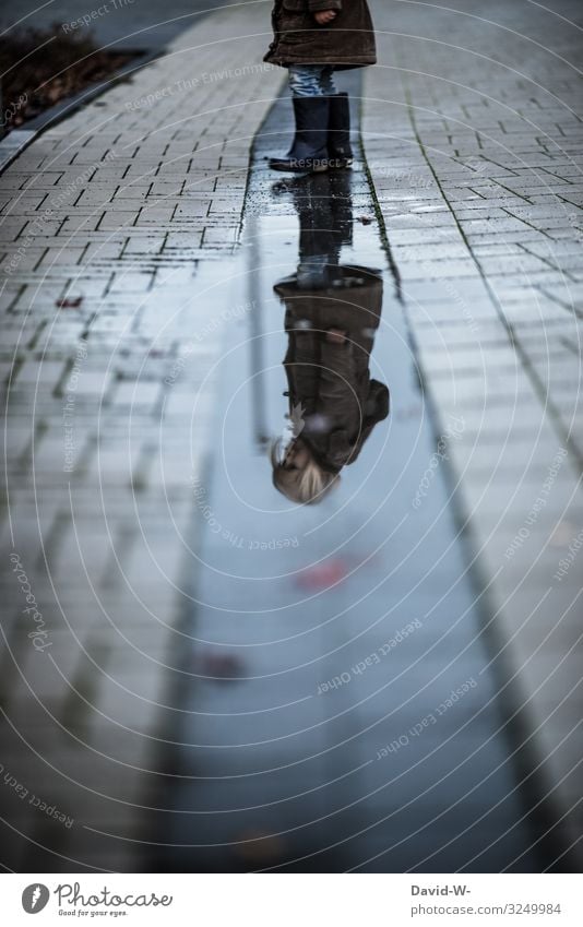 Kind spiegelt sich in einer Pfütze Spiegelbild Spiegelung Kindheit Zukunft Gedanken draußen Herbst Mädchen spielen herbstlich Regen nass schlechtes Wetter