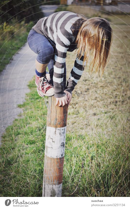 kletterin (2) Kind Mädchen jungennhaft Klettern Spielen gewagt Pfosten Holzpfahl Zaunpfahl festhalten Außenaufnahme Fußweg Natur toben Kindheit Geschicklichkeit