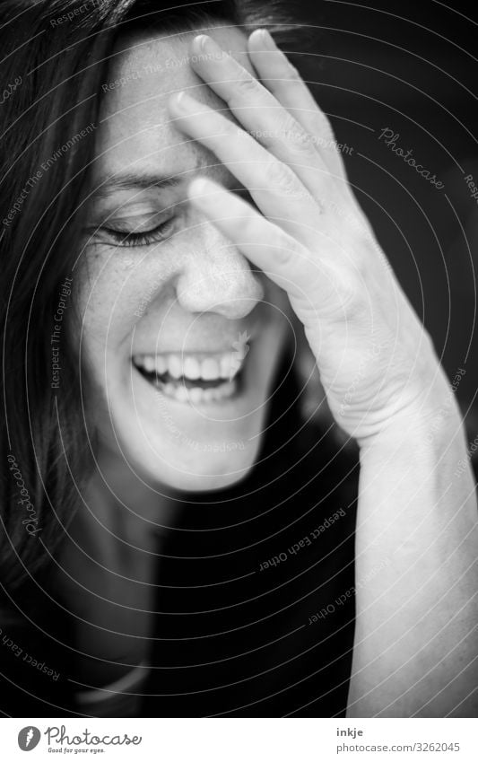 lachende Frau mit geschlossenen Augen und Hand an der Stirn Schwarzweißfoto Innenaufnahme Portrait Nahaufnahme Frauenportrait Lachen fröhlich amüsiert Geste