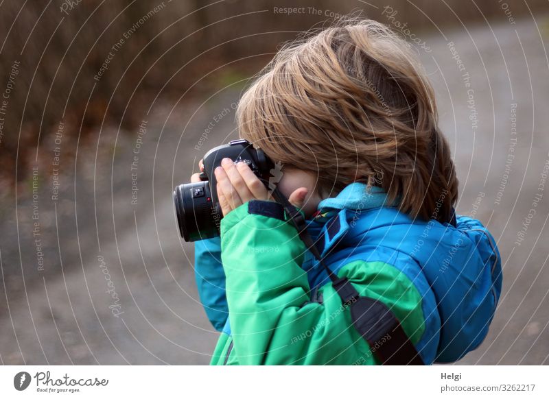 Profilaufnahme eines kleinen Jungen mit halblangen Haaren, der in eine Kamera schaut Fotokamera Mensch maskulin Kind Kindheit 1 3-8 Jahre Natur Winter