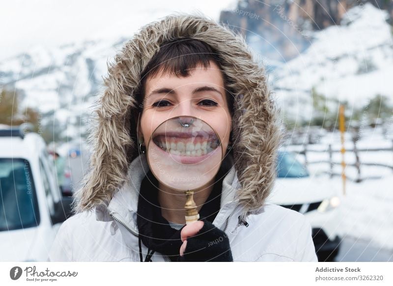 Frau lächelt im Winter durch die Lupe Zähne Lächeln interessiert Straße Landschaft Berge u. Gebirge Schnee leer Piercing Inhalt spielerisch Lachen weiß