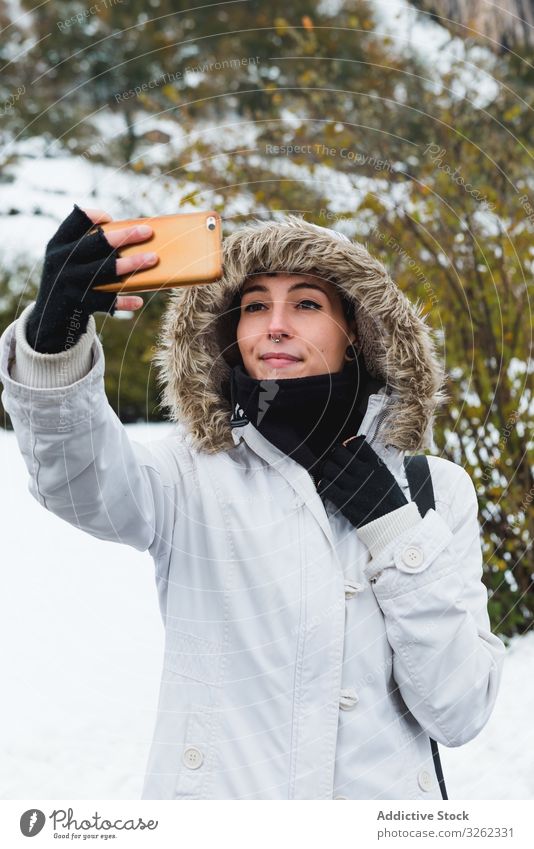 Frau, die sich im Winter an der Natur vergreift Selfie Handy Lächeln Inhalt Schnee Buchse Smartphone Spaziergang ruhen Feiertag Umwelt jung Glück aktiv