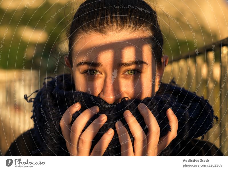 Erfreute junge Dame mit Schal an sonnigem Tag Frau laufen Deckung Lächeln grün Auge Inhalt zufrieden schlendernd Brücke Natur Schatten Lifestyle Herbst Straße