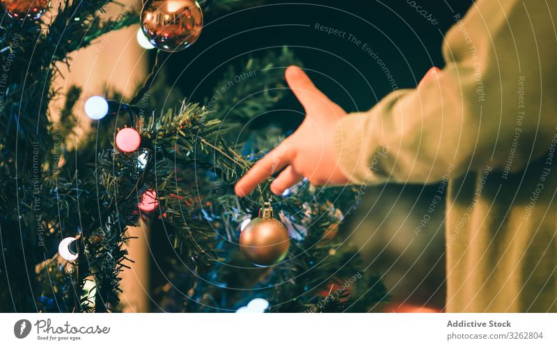 Junge schmückt Weihnachtsbaum am Abend Weihnachten Baum Dekor Feuerstelle Wohnzimmer hängen Kugel traditionell heimwärts Feier Kind wenig fröhlich Feiertag