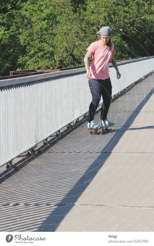 sportliche Dame fährt mit dem Scateboard auf eine Brücke, das Geländer wirft Schatten Sport Fitness Sport-Training Skateboard Mensch feminin Frau Erwachsene 1