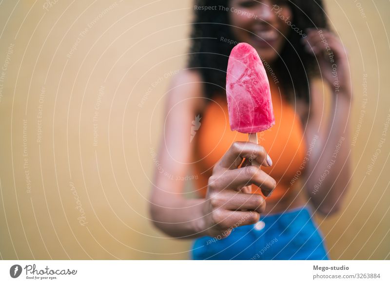 Afrofrau genießt den Sommer und isst ein Eis. Dessert Speiseeis Lifestyle Freude Glück schön Erholung Mensch Frau Erwachsene Hand Afro-Look genießen Lächeln