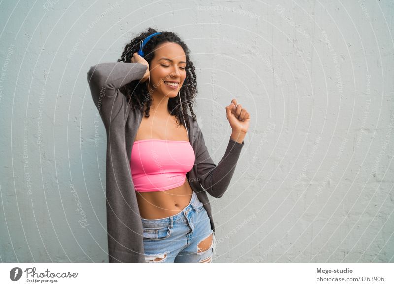 Junge Afrofrau, die mit Kopfhörern Musik hört. Lifestyle Stil Freude Glück schön Frau Erwachsene Afro-Look genießen hören Lächeln stehen Fröhlichkeit niedlich