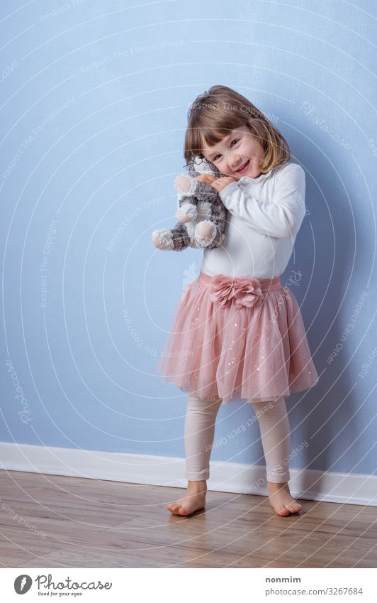 Das Mädchen umarmt ein flauschiges Katzenspielzeug, das auf dem Boden liegt. Freude Spielen Abenteuer Kind Freundschaft Spielzeug Teddybär Liebe träumen Umarmen