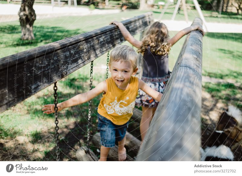 Lustige Kinder klettern an Sommertagen auf dem Spielplatz Abenteuer Spaß haben spielerisch Wiese Geschwister Klettern Baum Kindheit Natur Brücke Park aktiv