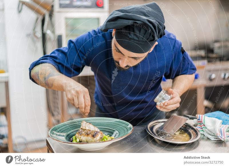 Koch, der Salz auf ein Gericht streut Küchenchef Arbeit Speise Teller Mann Lebensmittel dienen professionell Abfertigungsschalter Endbearbeitung vorbereiten