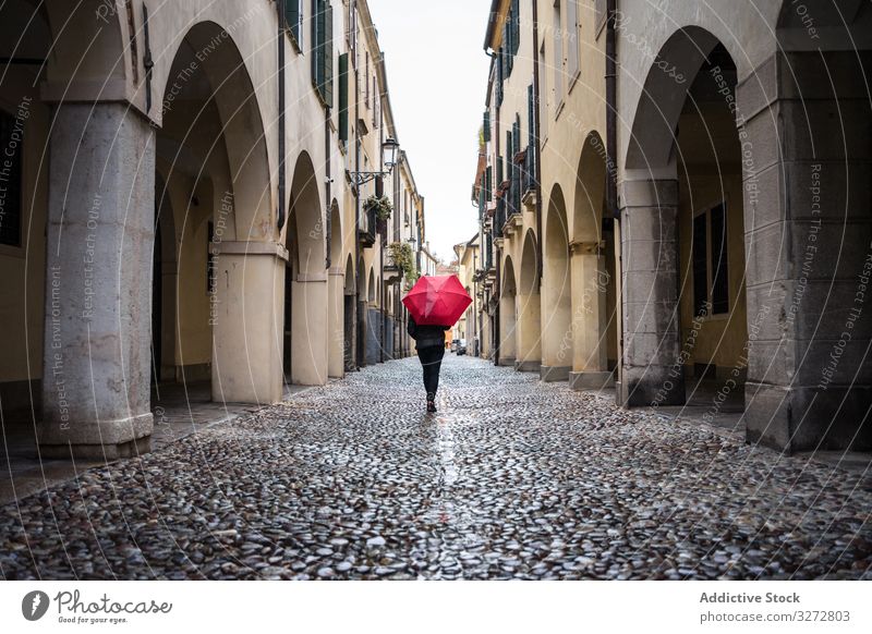 Tourist mit Regenschirm geht bei Regenwetter auf der Stadtstrasse spazieren Person Straße Großstadt laufen schlendernd erkunden Interesse nass Gebäude alt schön