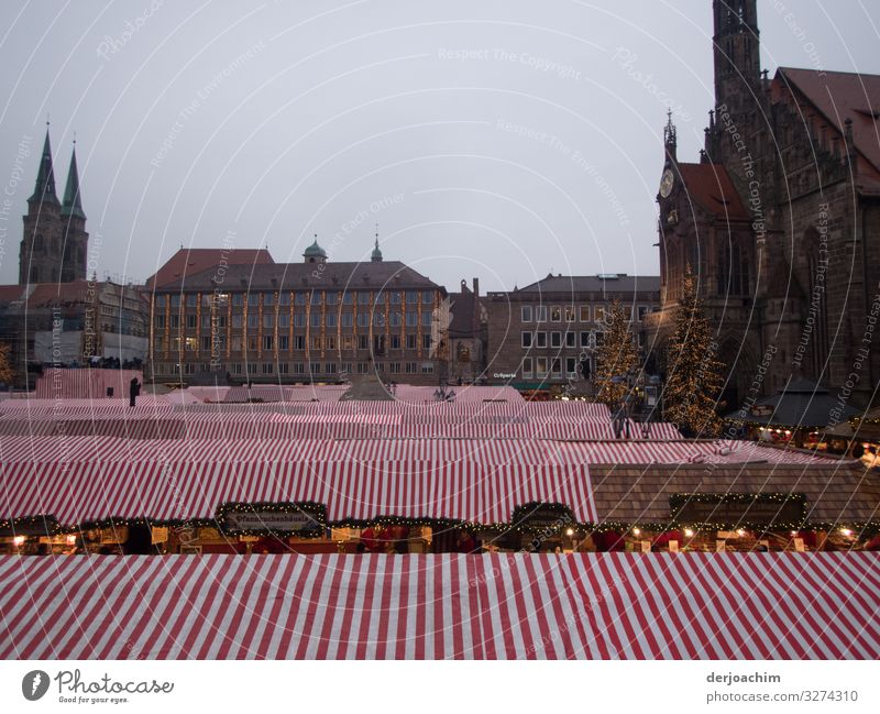 Überdacht ist der Weihnachtsmarkt in Nürnberg. . Die Stände sind mit Rot. Weiß Markisen  Überdacht. Im Hintergrund sind Fachwerkhäuser zu sehen. Freude Erholung