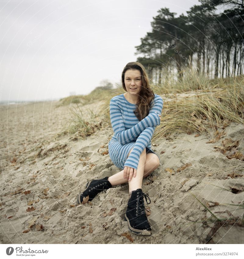 Junge Große Frau Sitzt Im Sommerkleid Am Ostseestrand Und Lächelt Ein Lizenzfreies Stock Foto 