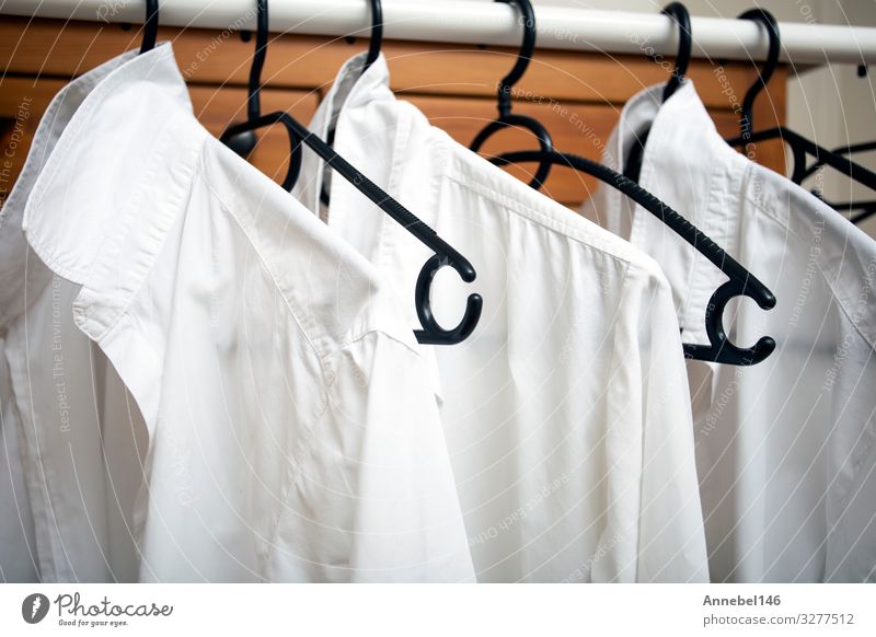 Reihe von weißen Baumwollkleidern hängen an schwarzen Bügeln auf einem Gestell kaufen Stil Design Büro Business Frau Erwachsene Mann Mode Bekleidung T-Shirt