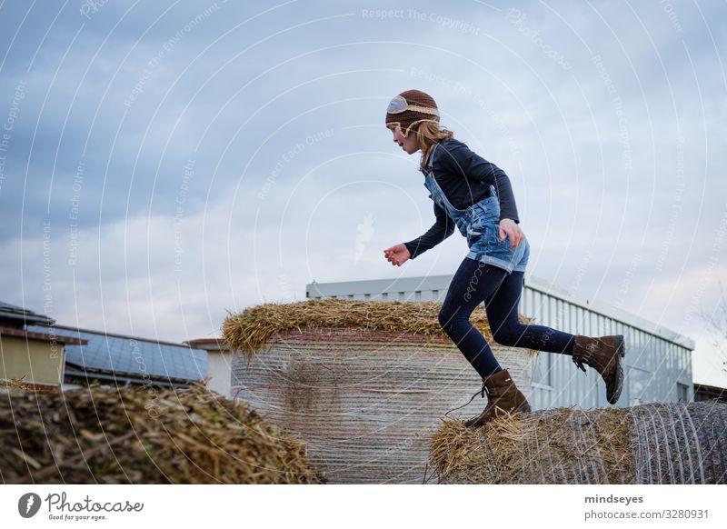 Mädchen springt über Strohballen Spielen Abenteuer Bauernhof Kind 1 Mensch 3-8 Jahre Kindheit Natur Mütze springen sportlich Fröhlichkeit frisch Glück