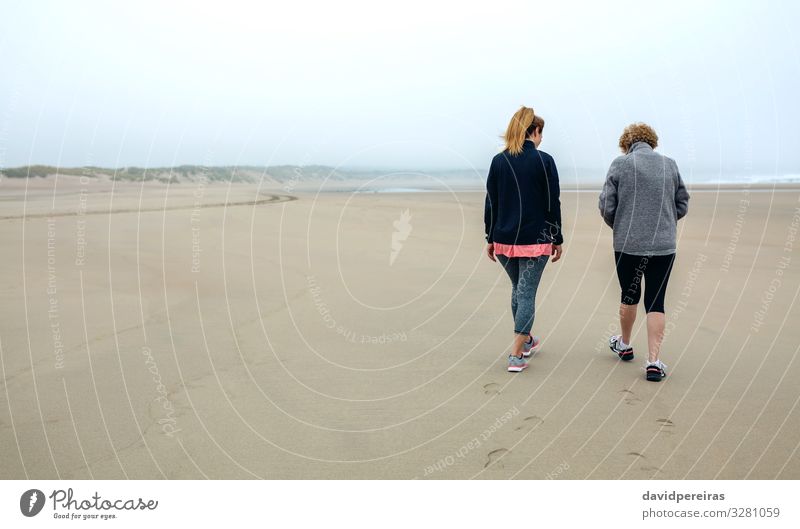 Rückenansicht von Frauen, die am Strand spazieren gehen Lifestyle Windstille Mensch Erwachsene Mutter Großmutter Familie & Verwandtschaft Sand Himmel Herbst