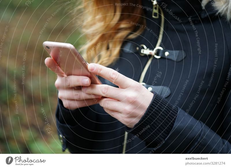 junge Frau nutzt Smartphone unterwegs Lifestyle Freizeit & Hobby Winter Telefon Handy PDA Technik & Technologie Unterhaltungselektronik Internet Mensch feminin