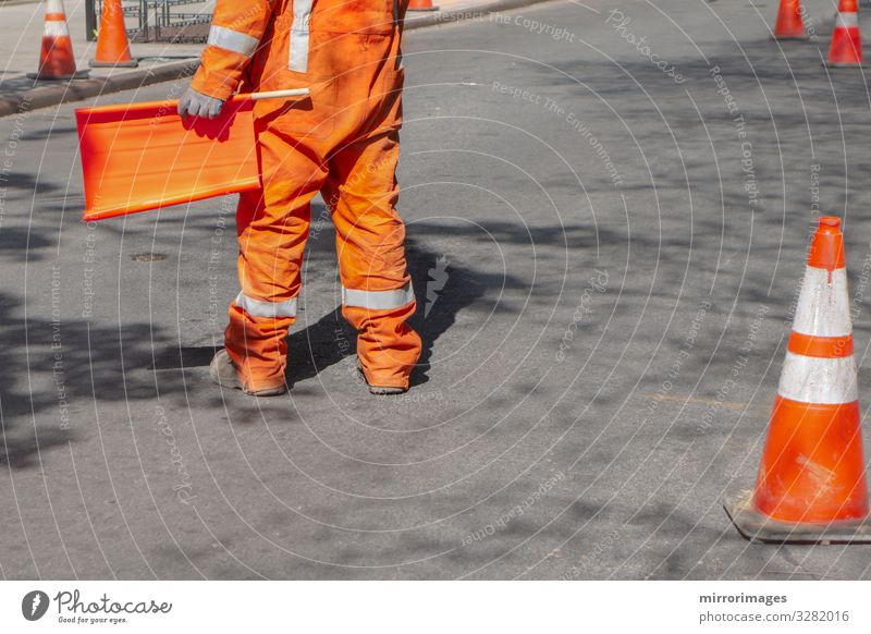 orangefarbener Mann, der den Verkehr mit orangefarbener Flagge auf einer Schwarzdecke lenkt Arbeit & Erwerbstätigkeit Beruf Baustelle Industrie Werkzeug Mensch