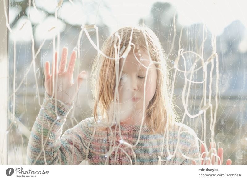 Mädchen steht im Freien hinter einer Glasscheibe mit geschlossenen Augen Häusliches Leben Haus Dekoration & Verzierung Lichterkette 1 Mensch 3-8 Jahre Kind