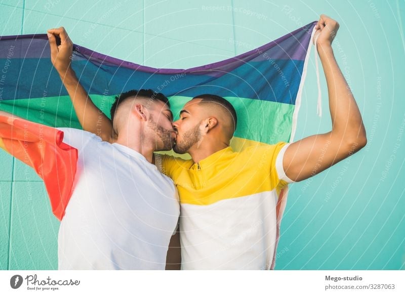 Schwules Paar umarmt und zeigt seine Liebe mit der Regenbogenfahne. Lifestyle Glück Freiheit Feste & Feiern Mensch Homosexualität Mann Erwachsene Partner Fahne
