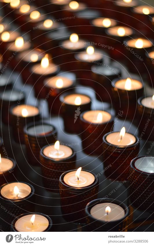 Reihen mit Kerzen in Gläsern in einer Kirche als Symbol fuer Gebet Feuer leuchten dunkel heiß hell viele Vertrauen trösten dankbar Ehrlichkeit Hoffnung Glaube