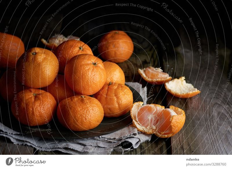 Haufen ungeschälter runder reifer orangefarbener Mandarinen Frucht Dessert Ernährung Vegetarische Ernährung Saft Teller Tisch Holz dunkel frisch natürlich