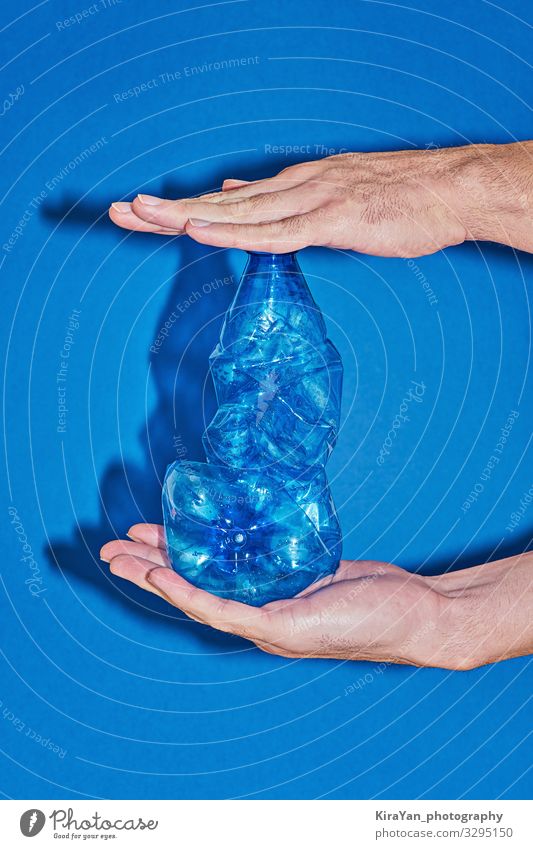 Zwei Hände, die eine Plastikflasche auf blauem Hintergrund drücken Flasche Lifestyle kaufen sparen Strand Meer Industrie Hand Umwelt Verpackung Kunststoff