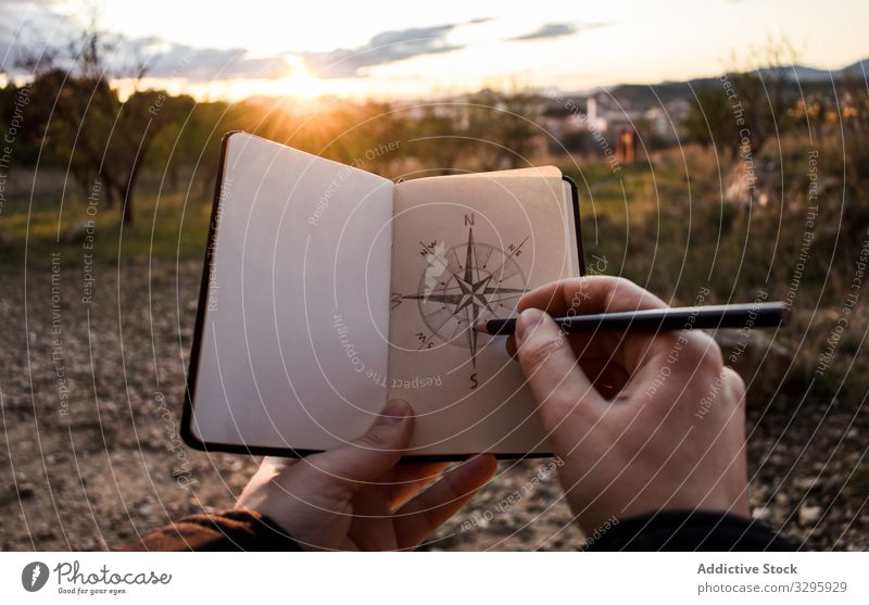 Pflanzenreisende ziehen Kompass während des Sonnenuntergangs Reisender Landschaft zeichnen Skizze Notebook Regie Abend Ausflug Urlaub Wochenende Abenteuer