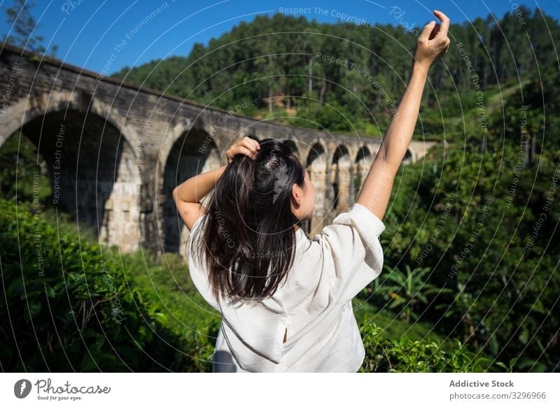 Junge Frau berührt Haare und genießt die Landschaft der alten Brücke grün Wald antik asiatisch Brücke mit neun Bögen schäbig ella Sri Lanka touristisch reisen