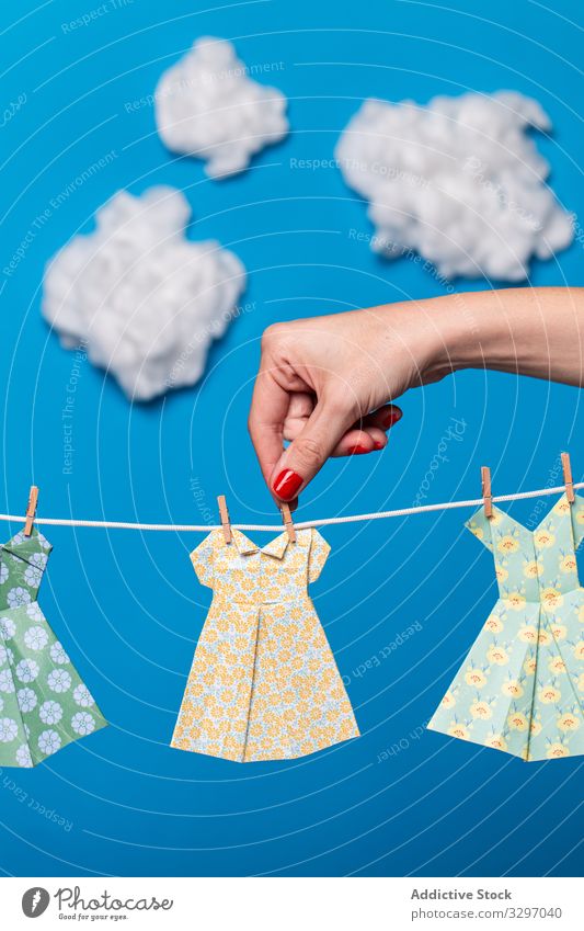 Nutzpflanzenfrau befestigt Origami-Kleider am Seil Frau Konzept befestigen hängen Sauberkeit Wäscherei Himmel Cloud hell lebhaft pulsierend Papier Attrappe