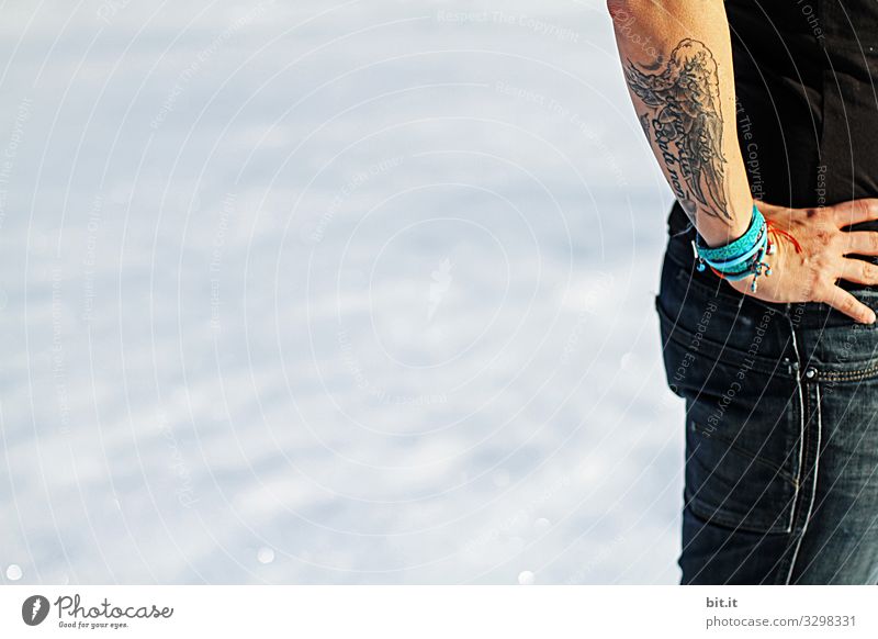 Hautsache l Arm und Hand einer tätowierten Frau, mit nackter Haut und Flügel als Tattoo im Winter draussen im Schnee, beim Wandern, Snowboarden oder Skifahren. .